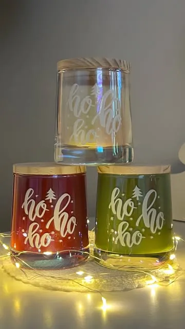 Três copos de vela de Natal com a gravação ho ho ho, em vermelho, verde e transparente